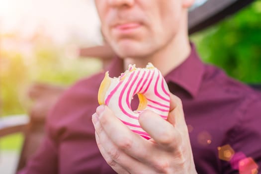 Close-up delicious glazed donut in the hands of an office worker during lunch outdoors