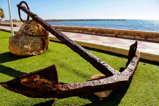 Old anchor on a promenade of Santa Pola, Alicante. Mediterranean sea on background.