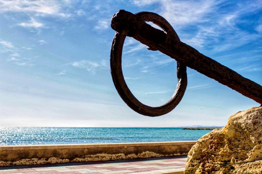 Old anchor on a promenade of Santa Pola, Alicante. Mediterranean sea on background.