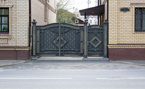 New forged metal double gates for entry of cars into the yard closed.