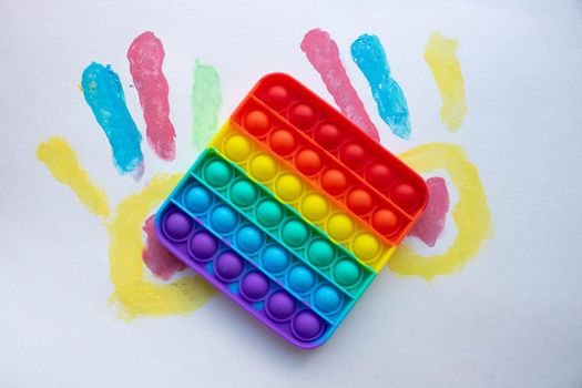 Pop it. A toy on a white background with colorful handprints. Blue and Orange Funny Interactive Anti-Stress Silicone Toys..