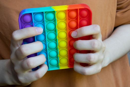 Hands hold a touch-sensitive fidget toy. Blue and Orange Funny Interactive Anti-stress Silicone Toys.