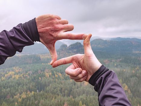 Hands make viewfinder from fingers. Wonderful mountains and sunrise natural background. 