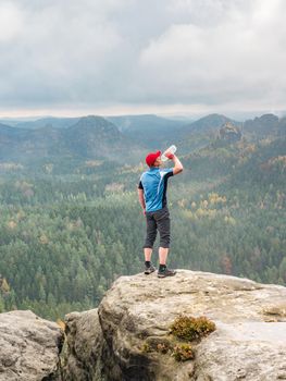 Thirsty Sportsman drinking on summit.  Man achieved personal peak, refreshing body power.