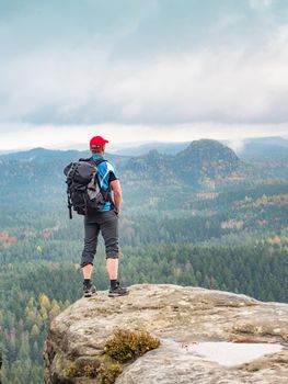 Sporty man hiker on the mountain peak looking on mountain valley with sunbeams at colorful sunset in autumn in Europe. Landscape with traveler