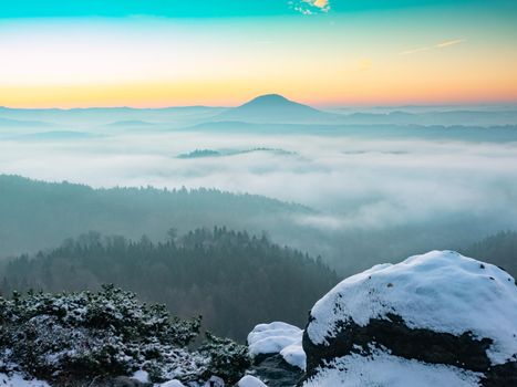 Mountain morning  landscape with fog and trees. Snowy rocks in foreground