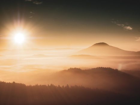 Orange mist above pure nature landscape. Romantic morning in hilly landscape