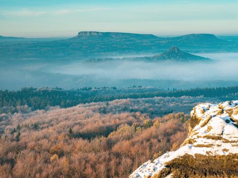 Snowy rocks above valley in Saxony Switzerland national park. Elbe river valley in chill morning