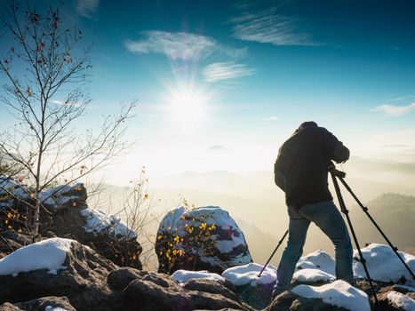 Nature photographer taking photos in the snowy mountains. Amazing winter morning