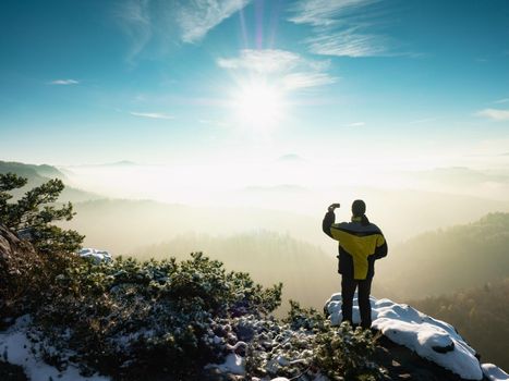 Man takes a photo on a mobile phone of a rocky ridge in winter morning. Beautiful landscape, hike, outdoor activities, tourism