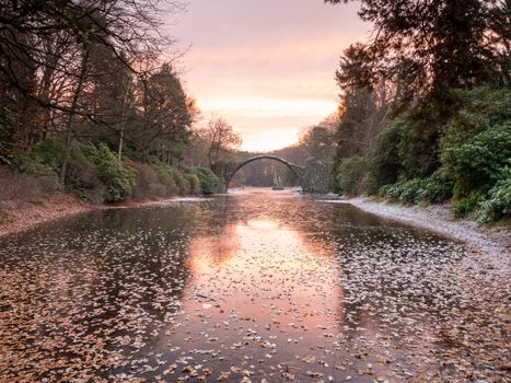 Winter night with  Rakotzbrücke over lake, Azalea and Rhododendron Park Kromlau. Amazing place in Germany. Rakotzbrucke also known as Devils Bridge.