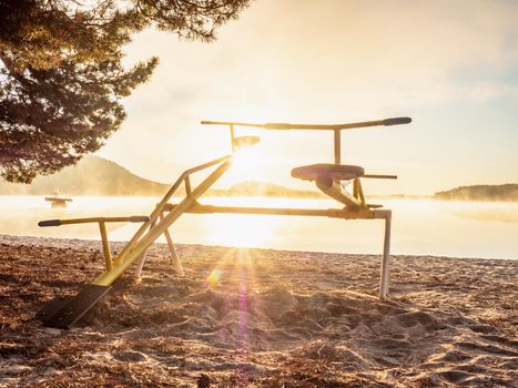 Colorful sunset with seesaw on beach. Teeter totter with wooden chairs,  sand balance close up outdoor playground