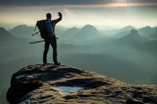 Silhouette of hiker with backpack and walking poles is going in mountains and sunset 