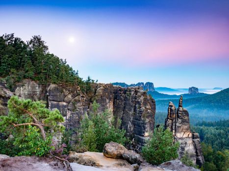 Damp night with the moon in the sunlight jagged jagged sandstone walls in Saxon Switzerland National Park.