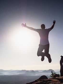 Success and freedom. The independence concept photo. Hiker jumps at the top of the mountains, with arms raised against sunrise.