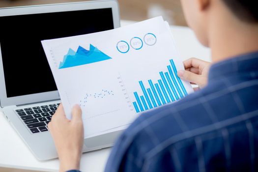 Hand of young business man looking document data graph and chart paper, marketing and investment, report of statistics profit for financial, economic and growth of finance, management and planning.
