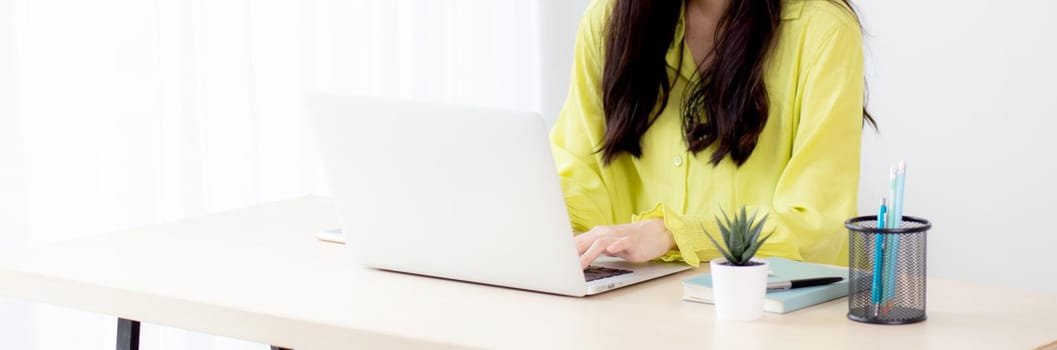 Young asian businesswoman working on laptop computer on desk at home office, freelance looking and typing on notebook on table, lifestyle of woman studying online, business and education concept.