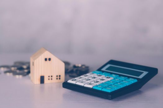 Investment about home with calculator and model house and coins on desk, property and real estate and mortgage, loan and finance, financial saving and account for residential, business concept.