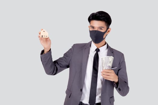 Young asian businessman in face mask holding money dollar and home isolated on white background, pandemic and crisis of economic, business man and investment property during disease covid-19.