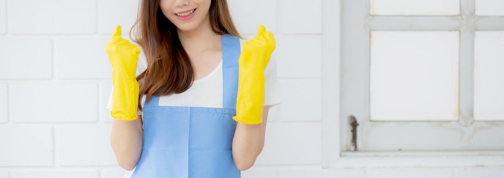 Portrait young asian woman is housekeeper in rubber gloves and apron for protection at home, uniform of maid, cleaning and washing, girl standing worker positive, one people, lifestyle concept.