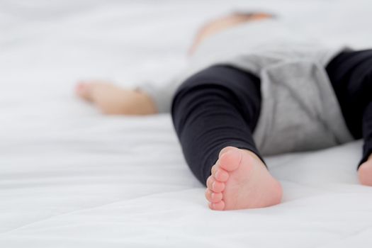 Closeup foot of asian little baby girl sleeping on bed in the bedroom at home, newborn napping with cozy and relax, infant innocence in bedtime, happy toddler cute, growth of child and emotion.