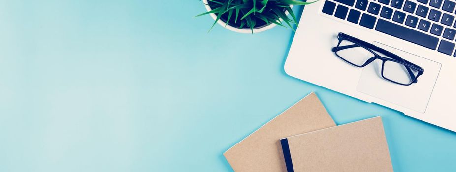 Flat lay of Laptop computer and plant on desk in office, workplace and notebook and glasses and potted tree and book, workspace and copy space, top view, object with above, nobody, business concept.