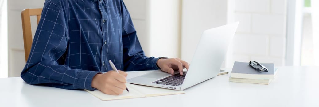 Young asian business man in face mask for protect covid-19 and work on laptop computer and writing notebook, businessman quarantine work from home, new normal, social distancing and stay home.