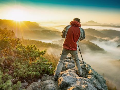 Photographer hiking talking photos using SLR camera in fall autumn forest. Man photographing in high mountains. 