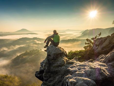 Hiking on mountain ridge in the summit of clouds. A happy man silhouette alone
