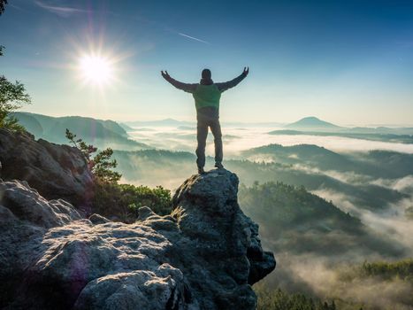 Alone single tourist raised arms for greetings of  stunning view of misty valley. Man enjoy the mountain look. 