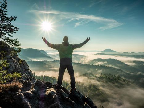 Hiking on mountain ridge in the summit of clouds. A happy man silhouette alone
