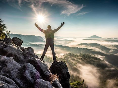 Hiking on mountain ridge in the summit of clouds. A happy man silhouette alone
