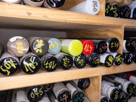 Color glass bars in wooden rack. Bunch of colorful glass rods on shelf by workstation in glass blowing art studio