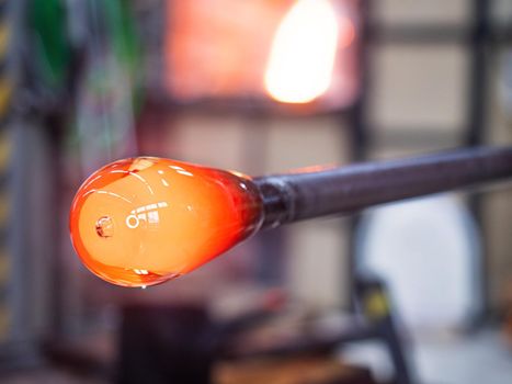 Manual shaping hot glass in art studio. Man designer is creating a fluted bowl from this piece of molten glass.