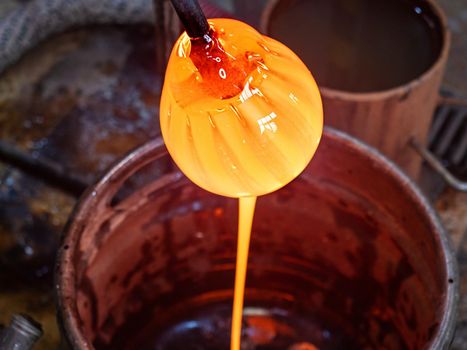 The glowing liquid glass flows into a collection container. The waist melted glass.