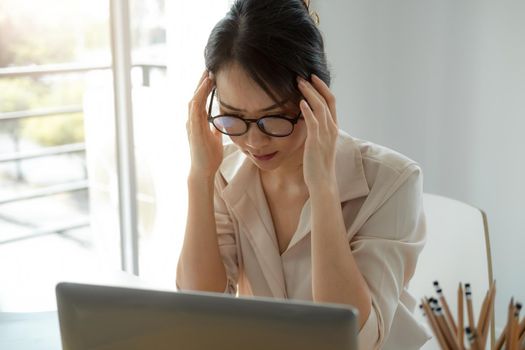Tired asian business woman with headache from laptop computer work feeling headache at office, feeling sick at work,