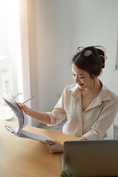 Female asian businesswoman analyzing the business report with laptop computer in the office