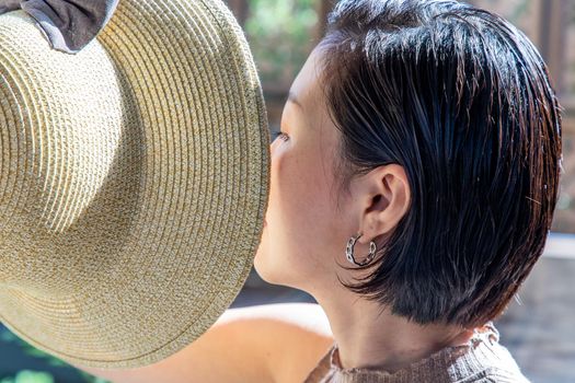 Young asian woman and short hair holds the brim of the Hat close-up. Selective focus.