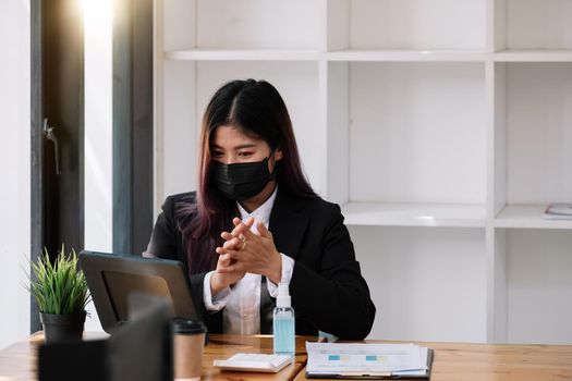 Businesswoman with face mask communicating with her colleague via video call while working in the office during COVID-19 pandemic.