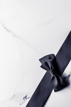 Holiday gift, decoration and sale promotion concept - Black silk ribbon and bow on marble background, flatlay