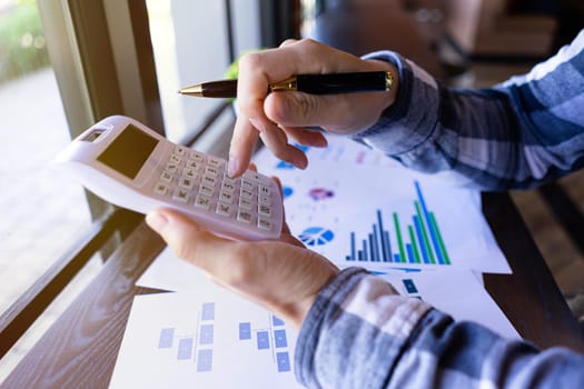 Businessman holding pen and press a calculator to calculate financial report or company's profit monthly. business financial accounting concept.