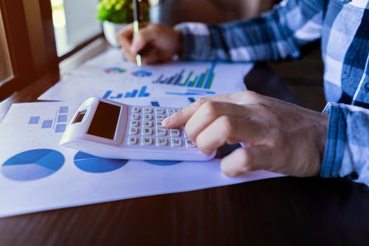 Businessman using a calculator to working in finance and accounting Analyze financial budget in the office.