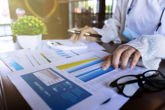 Close up businesswoman hand using calculator and pointing document about monthly expenses, managing budget, taxes statistic at home office.