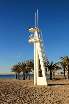 Lifeguard tower on a quiet and lonely beach in a sunny day in southern Spain, Alicante. Palm trees in the background.