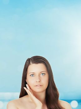 Skincare and sun protection in summer. Portrait of a beautiful young suntanned woman, blue sea and sky on background, beauty, wellness and travel concept.