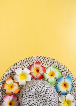 Summer and vacation concept. summer hat with plumeria flowers flat lay on yellow background