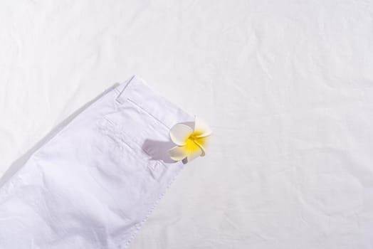 Summer and vacation concept. White summer jeans with plumeria flower on white background. Mock up design