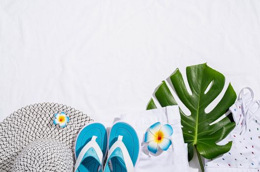 Summer and vacation concept. summer accessories with clothes, shoes, tropical leaves and flowers, flat lay on white babric background