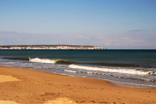 Sunny day on the beach in winter in La Marina, Alicante. Santa Pola on the background
