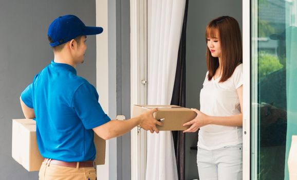 Asian beautiful customer young woman signing delivery in clipboard get her package from service courier man, smiling female signature receipt of delivery package at door front house
